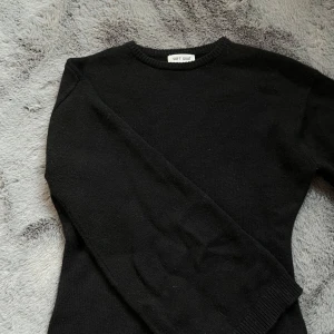 Svart kashmirtröja från Soft Goat XS - En klassisk svart rundhalsad tröja från Soft Goat i mjuk kashmir. Tröjan har lång ärm, ribbade muddar och en clean, tidlös look som funkar till allt. Perfekt för dig som gillar minimalistisk stil och vill ha något riktigt skönt och snyggt.