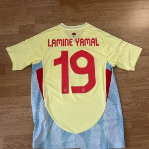 Spaniens Lamine Yamal matchtröja  - Spaniens bortaställ i storlek S med Lamine Yamal 19 tryck på ryggen.