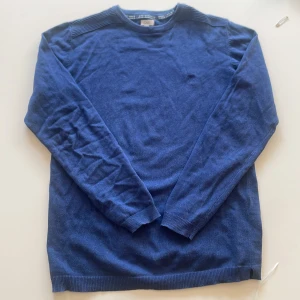 Blå stickad tröja från OVS - Mysig blå stickad tröja från OVS med rund halsringning och diskret broderad logga på bröstet. Tröjan har ribbade muddar vid ärmslut och nederkant samt långärmad passform. Perfekt för lager-på-lager under kyliga dagar.