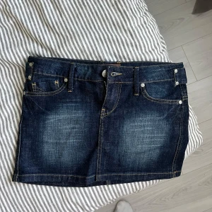 Lågmidjad jeanskjol  - SÅ snygg mörkblå lågmidjad jeanskjol med klassiska fem fickor, bälteshällor och dragkedja framtill. Kjolen har inga defekter eller tecken på användning (ser nästintill ny ut). 