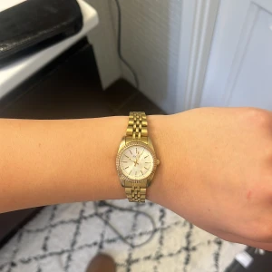 Guldig klocka från Regal med länkarmband - Snygg guldig klocka från Regal, välanvänd, men köpt ny så säljer denna, har extra länkdelar till armbandet som kommer med så att man kan justera storleken på klockan!!