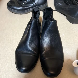 Stilrena svarta boots - 🖤 Stilrena svarta boots – storlek 41 🖤 Märke: DS – Shoes by Din Sko  Säljer ett par klassiska svarta boots i fint skick! Perfekta till både vardag och mer uppklädda tillfällen. Gjorda i mjukt syntetläder med elastiska sidor för enkel påtagning. Sköna att gå i och lätta att matcha till det mesta.  🧼 Rengjorda och redo för ny ägare. 📏 Storlek: 41 🛍️ Nypris: ca 499–599 kr 💸 Mitt pris: 200 kr