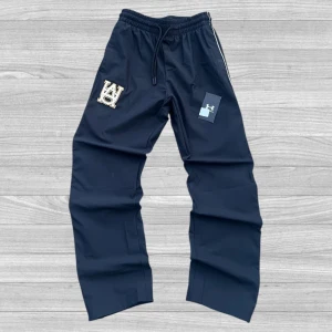 Under Armour byxor - Svarta träningsbyxor från Under Armour med vita ränder längs sidorna och broderad logga på benet. Byxorna har elastisk midja med snörning och är tillverkade i ett lätt syntetmaterial. Passformen är loose och modellen är rak i benen. Nypris: 1149kr