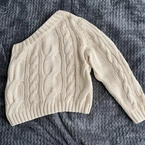 Beige stickad tröja från Gina Tricot - Säljer en chunky beige stickad tröja från Gina Tricot med grovt flätmönster. Tröjan har lång ärm, bred ribbad kant och en mysig, oversized känsla. 