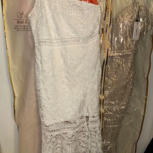 Vit spetsklänning från boohooo - Superfin vit långklänning från Sasha med vacker spets och blommigt mönster. Klänningen har en ärmlös design och en snygg slits nertill. Perfekt för dig som vill ha en romantisk och elegant look.