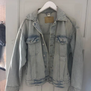 Ljusblå oversized jeansjacka  - Säljer en ljusblå jeansjacka med klassisk passform och snygga sömdetaljer. Jackan har två bröstfickor med knappar, långa ärmar och silverfärgade knappar framtill. Perfekt att slänga över en hoodie eller crop top.