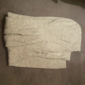 Ljusgrå hoodie med snörning - Mysig ljusgrå hoodie med långa ärmar och huva. Tröjan har snörning vid halsen och är tillverkad i ett mjukt stickat material. Perfekt för chill dagar och enkel att matcha med jeans eller mjukisbyxor.