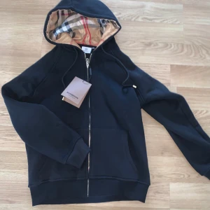 Svart burberry kofta/hoodie - Säljer denna kofta från burberry i storlek M, koftan var för liten på mig men är helt ny, materialet är 10/10, varm och mjuk. Ordinarie pris på denna går för 2000kr +. Tveka inte på att höra av er, pris KAN diskuteras 