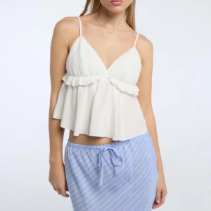 Vit volangig linnetopp med smala band - Supersöt vit linnetopp med smala axelband. Aldrig använt💗