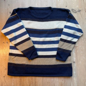 Randig stickad tröja i blått och beige - En stickad tröja köpt i Köpenhamn. Står ingen storlek men den är ca M. Riktigt skön och bra färger har den också! Skriv vid intresse.