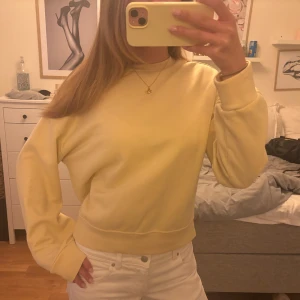 Ljusgul sweatshirt med loose fit - En enkel och fräsch ljusgul sweatshirt med rund hals och långa ärmar. Tröjan har en loose passform och breda muddar vid ärmslut och nederkant. Perfekt för dig som gillar en clean och chill stil. Materialet känns mjukt och är troligtvis bomull eller polyester.