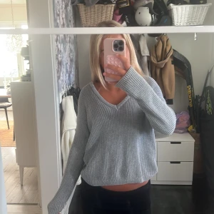 Grå ribbad stickad tröja NA-KD - Säljer en chill grå stickad tröja från NA-KD i storlek XXS. Tröjan har ribbad struktur, v-ringad hals och långa ärmar. Perfekt för lager-på-lager och passar dig som gillar en loose fit. Enkel att matcha med jeans eller kjol.