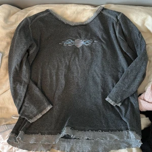 Grå Harley Davidson långärmad tröja - Säljer en grå långärmad tröja från Harley Davidson med tryck och broderad logga fram och bak. Tröjan har råa kanter och coolt tribal-mönster på bröstet. Materialet är mjukt och känns som bomull. Passar dig som gillar edgy och avslappnad stil.