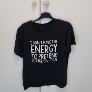 Svart t-shirt med statement-tryck - Svart t-shirt med vit statement-text: 'I DON'T HAVE THE ENERGY TO PRETEND TO LIKE YOU TODAY' på framsidan. Rund hals, korta ärmar och rak passform. Materialet är mjukt med lite stretch för skön känsla. I storlek M från Shein. 💓💓
