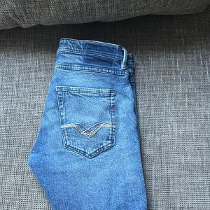 Replay Willbi blå jeans regular slim - Säljer ett par Replay Willbi jeans i klassisk blå tvätt med regular slim fit. Ny pris 2000kr.Jeansen har snygga slitningar och detaljer på benen samt broderad bakficka. Passar dig som gillar en modern och avslappnad stil. Materialet är jeans och de har fem fickor och knappgylf.