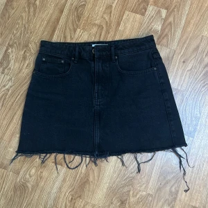 Svart jeanskjol från Zara - Svart jeanskjol från Zara med fransig kant nedtill. Färgen är urtvättat svart, alltså lite gråaktig, i original - syns bra på sista bilden.