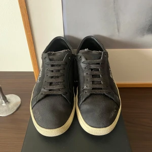 Saint Laurent SL/06 - Vi säljer nu dessa extremt fina och eftertraktade Saint Laurent SL/06 i den mest populära färgen. Size 42, Cond 8/10. Dessa par skor är riktigt schyssta. Det medföljer box, kort från YSL, 2 stycken nya skosnören, och två stycken stora dustbags. Dessa skor har tecken på användning på sulan och på ett av skosnörena där slutet ramlat av på snöret. Skorna är lite solblekta men utöver detta är skorna i ett väldigt fint skick. 