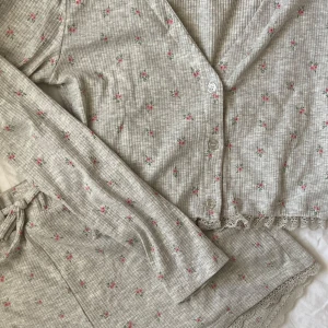 Blommigt pyjamas sett - Super gulligt pyjamas sett med en långärmad tröja och matchande shorts🌸 Grå färg med små rosa blommor och spetsdetaljer. storleken på shortsen är S och tröjan är en M, settet skulle passa bra på båda storlekarna💕Knappt använt! 