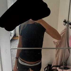 Svart tight t-shirt med ribbade detaljer - Snygg svart skön tränings t-shirt med korta ärmar och rund hals. Modellen är tight och har ribbade muddar vid ärmslut och nederkant för en schysst passform. 