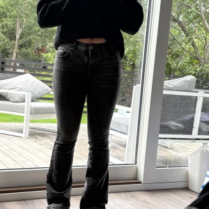Svarta bootcut jeans med stretch - Snygga gråa jeans med bootcut-snitt och klassisk femficksdesign. Jeansen har en mörk tvätt och sitter tajt över låren innan de blir vidare nedtill. Midjan är normal och materialet är stretchigt jeans för skön passform. Perfekta för dig som gillar en cool och tidlös look.
