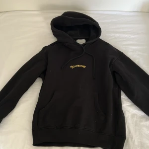 Svart Yellowstone hoodie med tryck - Svart hoodie från Valiente med gul 'Yellowstone' text på bröstet och stort tryck med National Park motiv. 