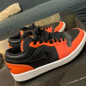 Nike Jordan 1 Low svart och orange - Säljer ett par Nike Jordan 1 Low i väldigt gott skick. Äkta. Storlek 40,5. 