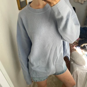Ljusblå stickad cashmere tröja oversized - Supermysig ljusblå stickad tröja med oversized passform och långa ärmar. Tröjan har breda ribbade muddar vid hals, ärmslut och nederkant. Perfekt för chill dagar och enkel att styla med jeans eller shorts.