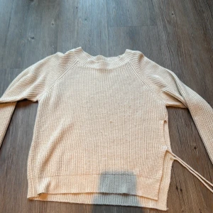 Beige stickad tröja från SHEIN - Säljer en beige stickad tröja från SHEIN i storlek S. Tröjan har rund hals, långa ärmar och ribbade muddar. Snygg detalj med snörning i sidan som ger en cool touch. Perfekt för lager-på-lager och chill höst- eller vinterstil.
