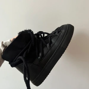 Svarta sneakers från Inuikii - Snygga svarta sneakers från Inuikii med hög design och snörning. Skorna har en robust sula och är perfekta för en stilren look. De är tillverkade i en kombination av skinn och mocka vilket ger en exklusiv känsla. Säljer pga för stora för mig. Köpte fel storlek 