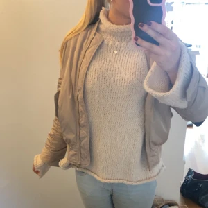 Beige bomberjacka - Säljer en snygg beige bomberjacka med dragkedja. Jackan har en klassisk bomberstil med ribbade muddar vid ärmslut och nederkant. Perfekt för höst och vår! 
