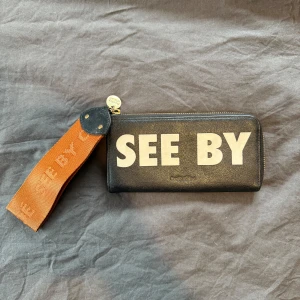 Svart plånbok från Chloé - Snygg svart plånbok från See By Chloé med stor vit text på framsidan. . Perfekt för att hålla ordning på kort och kontanter.