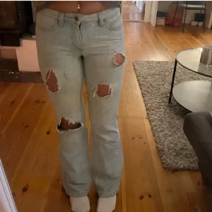 Ljusa jeans med slitningar - Snygga ljusa jeans med slitningar på knäna och låren. De har en klassisk femficksdesign och en knappgylf. Perfekta för en avslappnad stil.