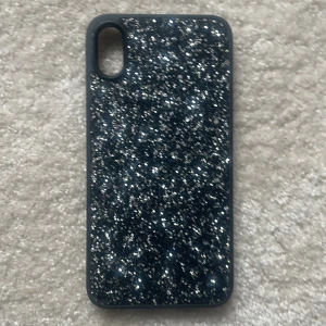 Glittrigt mobilskal för iPhone - Snyggt glittrigt mobilskal från Ideal of Sweden för iPhone. Skalet har en svart bas med silverglitter som ger en lyxig känsla. Perfekt för att ge din telefon ett stilfullt utseende samtidigt som den skyddas mot repor och stötar. Till iPhone xs