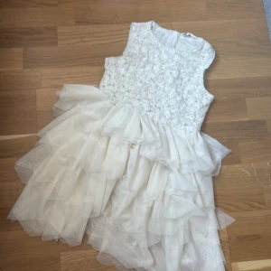 Vit ärmlös klänning från H&M - Säljer en söt vit klänning från H&M med spetsdetaljer på överdelen och volanger på kjolen. Klänningen är ärmlös och har en dragkedja i ryggen. Perfekt för speciella tillfällen! 🌟