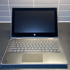 HP Laptop - Säljer en HP laptop med en stilren design. Den har en svart skärm och ett grått tangentbord. Perfekt för både arbete och studier. Locket är silverfärgat med HP-logotypen i mitten. Tangentbordet är bekvämt och pekplattan är rymlig.