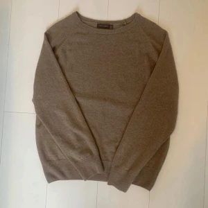 Beige merino/kashmir tröja från Oscar Jacobson - Säljer en stilren beige tröja från Oscar Jacobson, tillverkad i Italien. Tröjan har en klassisk design med långa ärmar och rund halsringning. Perfekt för en elegant och avslappnad look. Blend kashmir och merino