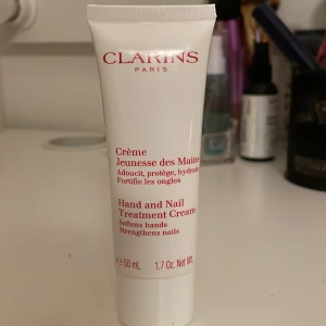 Clarins Hand and Nail Treatment Cream - Clarins Hand and Nail Treatment Cream är en lyxig handkräm som mjukgör och skyddar händerna samtidigt som den stärker naglarna. Den kommer i en praktisk tub på 50 ml, perfekt för att ha med i väskan. Krämen har en lätt och behaglig doft och absorberas snabbt utan att kännas kladdig.