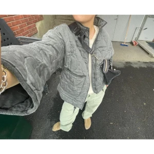 Grå quiltad jacka från Zara - Säljer en grå quiltad jacka från Zara med dragkedja och hög krage. Jackan har en loose passform och långa ärmar. Perfekt för kyligare dagar med sin stilrena design och bekväma känsla.