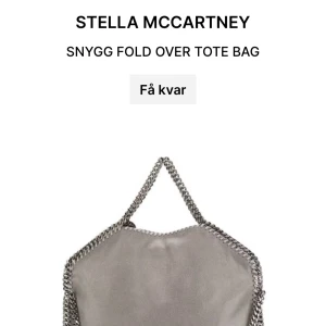 Grå tote bag från Stella McCartney - Snygg grå fold over tote bag från Stella McCartney med kedjedetaljer och en rund logotypbricka. Köptes på Plick. Inte i nyskick. Kol privat för egna bilder på väskan/ frågor