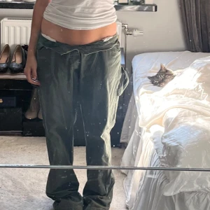 Gröna cargopants med knytband - Säljer ett par gröna cargopants med knytband i midjan. Byxorna har en loose passform. De har flera fickor och en avslappnad look. Saknar en knapp men är lätt att sy på en💞🥰