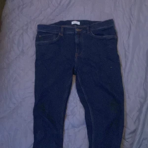 Mörkblå jeans från GANT - Snygga mörkblå jeans från GANT med klassisk design. De har en knappgylf och femficksmodell. Perfekta för en stilren look. Den passar om du e runt 178,185 cm