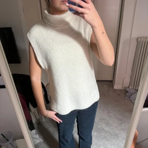 Vit ärmlös stickad topp från Zara - Säljer en stilren vit ärmlös stickad topp från Zapa. Toppen har en hög krage och en lös passform, perfekt för lager-på-lager eller som den är. Den har en mjuk och bekväm textur.