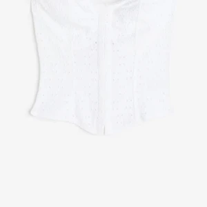 Vit broderad korsett  - Säljer en stilren vit korsett med vackra broderade detaljer. Den är axelbandslös och har en tight passform som framhäver figuren. Perfekt för att ge en elegant touch till din outfit. Slutsåld överallt