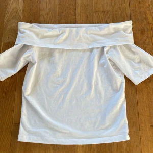 Vit offshoulder topp från LMTD - Säljer en stilren vit offshoulder topp från LMTD. Toppen har korta ärmar och en bred krage som ger en elegant look. Perfekt för varma dagar eller sommarens fester. Passar tonåringar i storlek S.