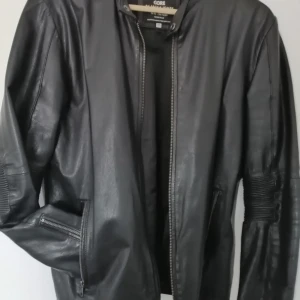 Svart skinnjacka från Jack & Jones - Snygg svart skinnjacka från Jack & Jones med dragkedja framtill och ribbade detaljer på ärmarna. Jackan har en stilren design och är perfekt för en cool look. Passar bra till både jeans och chinos.