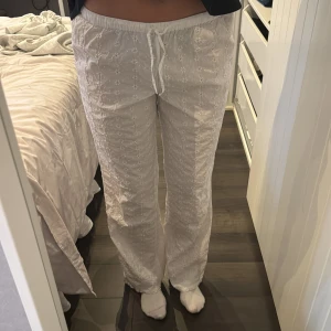 Vita broderade byxor med snörning - Säljer ett par vita byxor med broderade blommor och snörning i midjan. 