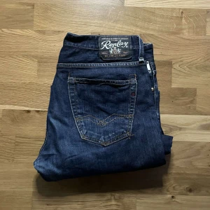Replay jeans  - Säljer ett par mörkblå jeans från Replay med klassisk femficksdesign och snygga kontrastsömmar. Jeansen har bootcut-passform och är tillverkade i slitstarkt denim. Märkespatch bak och metallmärke fram ger extra detaljer. Perfekta för dig som gillar en tidlös jeanslook.