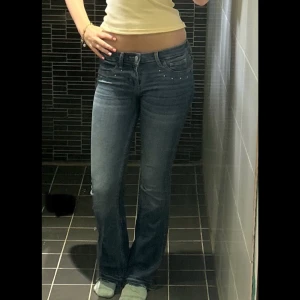 Lågmidjade jeans - Snygga blå bootcut jeans från Hollister med låg midja och små ”diamanter” vid framfickorna och mönster på bakfickorna. Storlek W25/L31 - uppsprättade, jag är 170 🩷