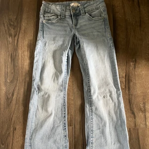 Ljusblå jeans från Gina Tricot - Snygga ljusblå jeans från Gina Tricot med klassisk femficksdesign och raka ben. Jeansen har detaljerade bakfickor med knapp och är tillverkade i mjukt denimtyg. Perfekta för en avslappnad och trendig look. Super fina och bara använda ett par få gånger!