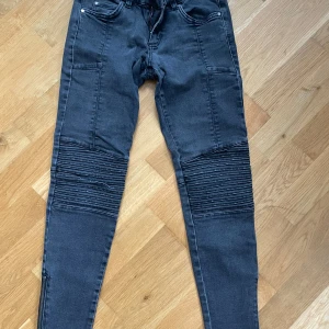 Svarta skinny jeans med dragkedjor - Snygga svarta skinny jeans från Zoul Edition med coola ribbade detaljer över knäna och dragkedjor vid bensluten. Jeansen har klassisk femficksdesign och är tillverkade i stretchigt jeanstyg för en tight passform.